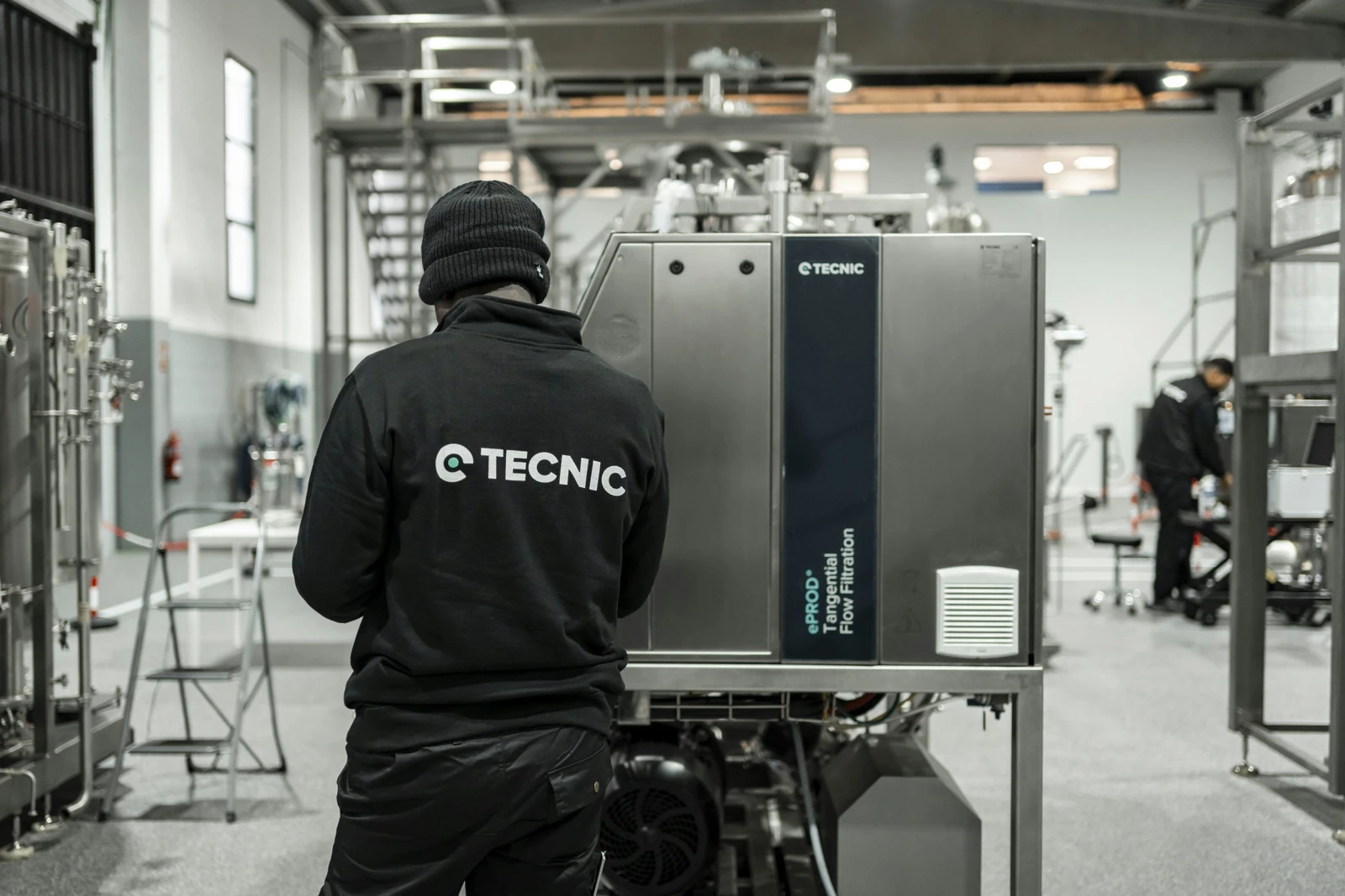 Engineer performing maintenance on stainless-steel processing equipment inside a clean manufacturing facility.
